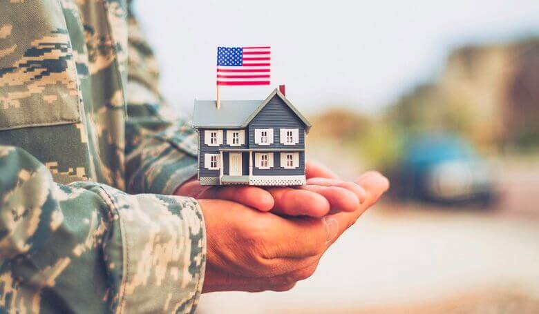 Picture of a military member holding a miniature home in their hands.