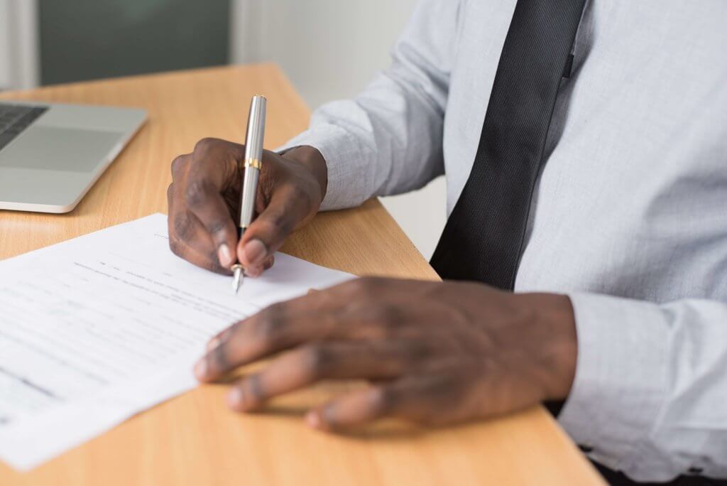 Close up of man's hands as he is signing a document.