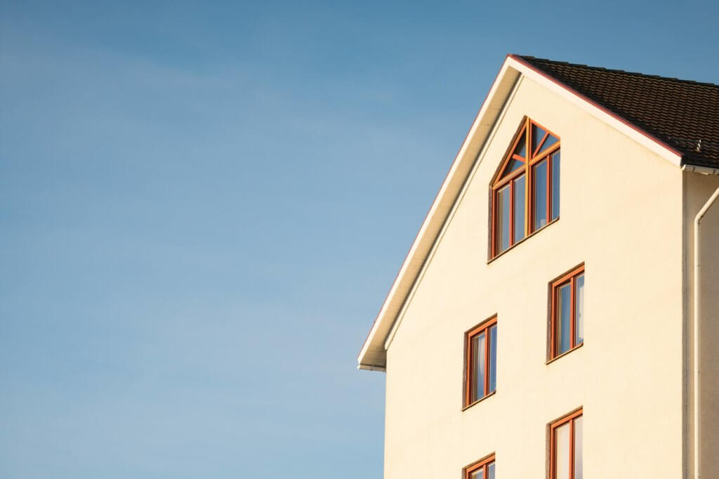 Side of a beige house with the sky in the background.